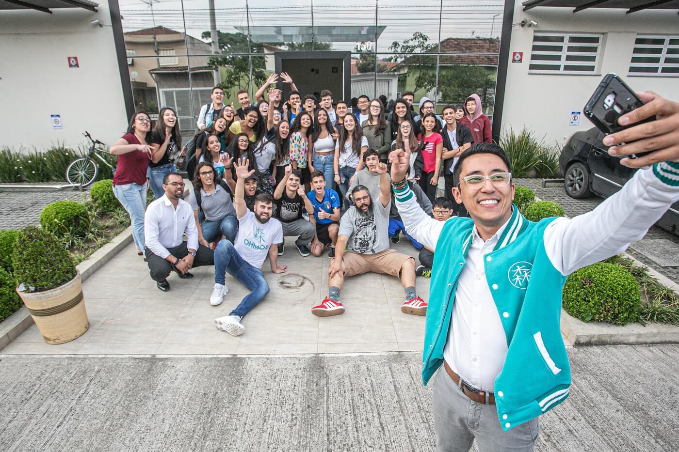Marco Ohmori faz selfie com dezenas de alunos na frente da escola durante gravação da Globo